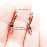 Assorted colorful cubic zirconia charms on titanium body jewelry by Body Clickers, featuring emerald, blue, and pink tones for piercings.