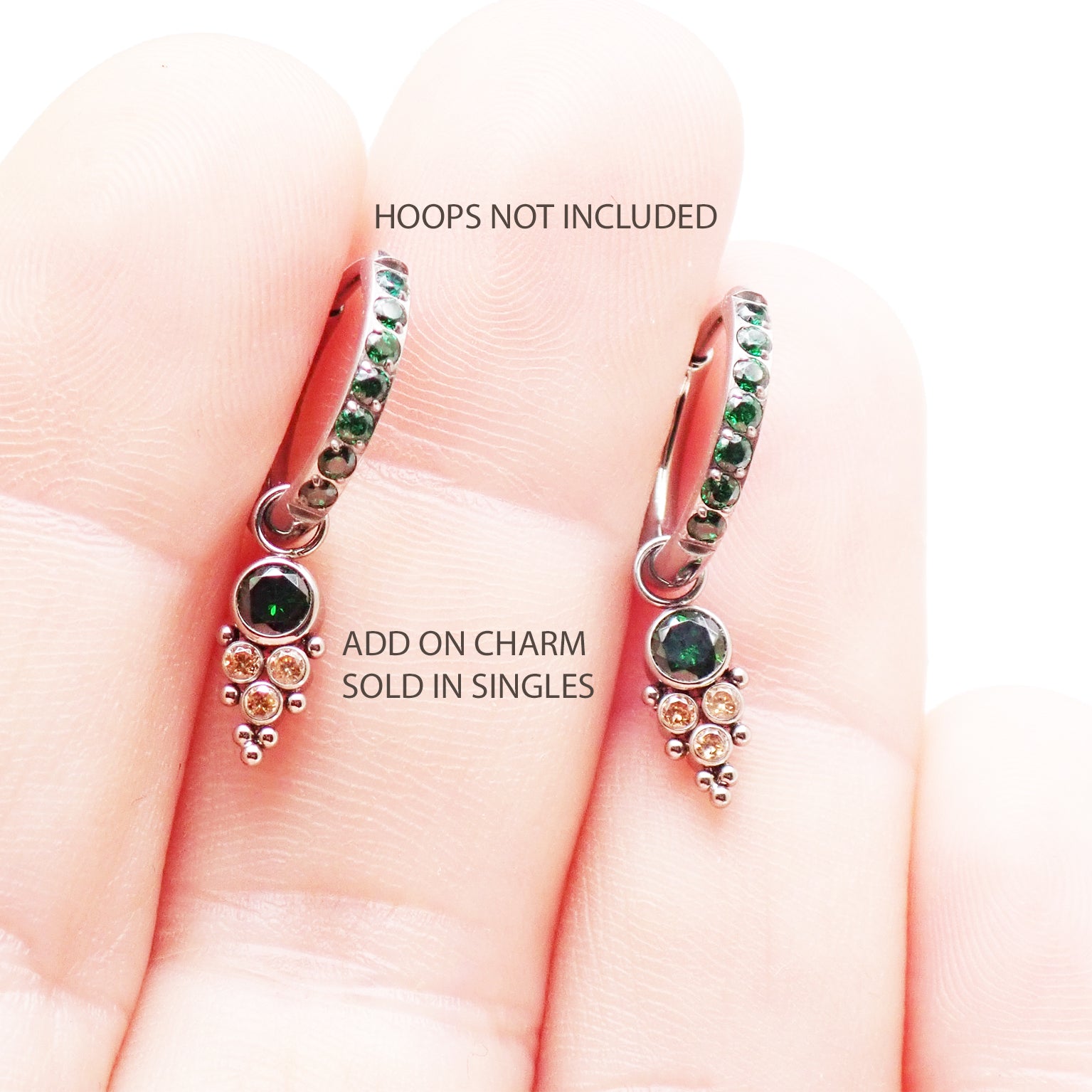 Assorted colorful cubic zirconia charms on titanium body jewelry by Body Clickers, featuring emerald, blue, and pink tones for piercings.