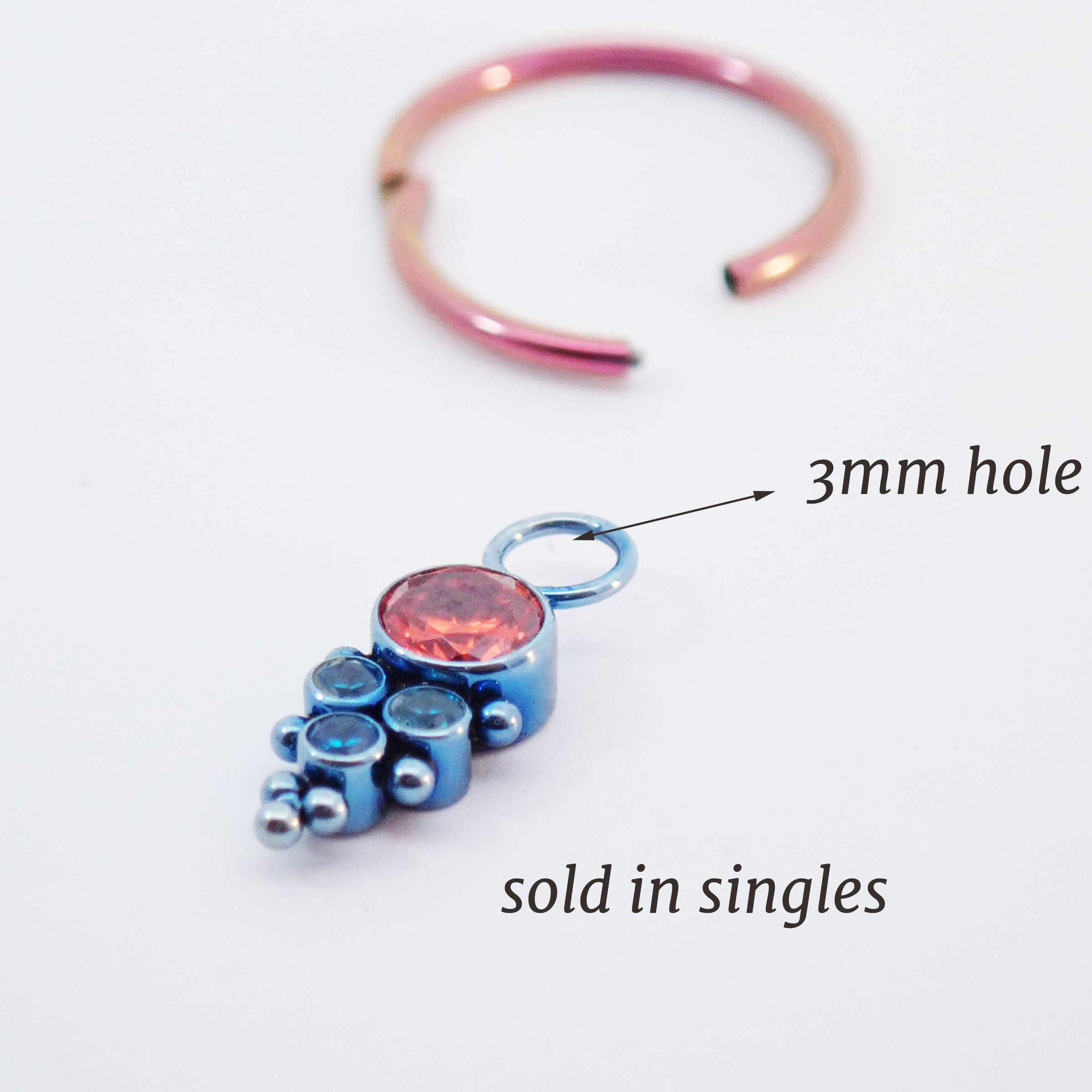 Assorted CZ charm colors on titanium body jewelry with orange and teal charms, designed for piercings from Body Clickers.