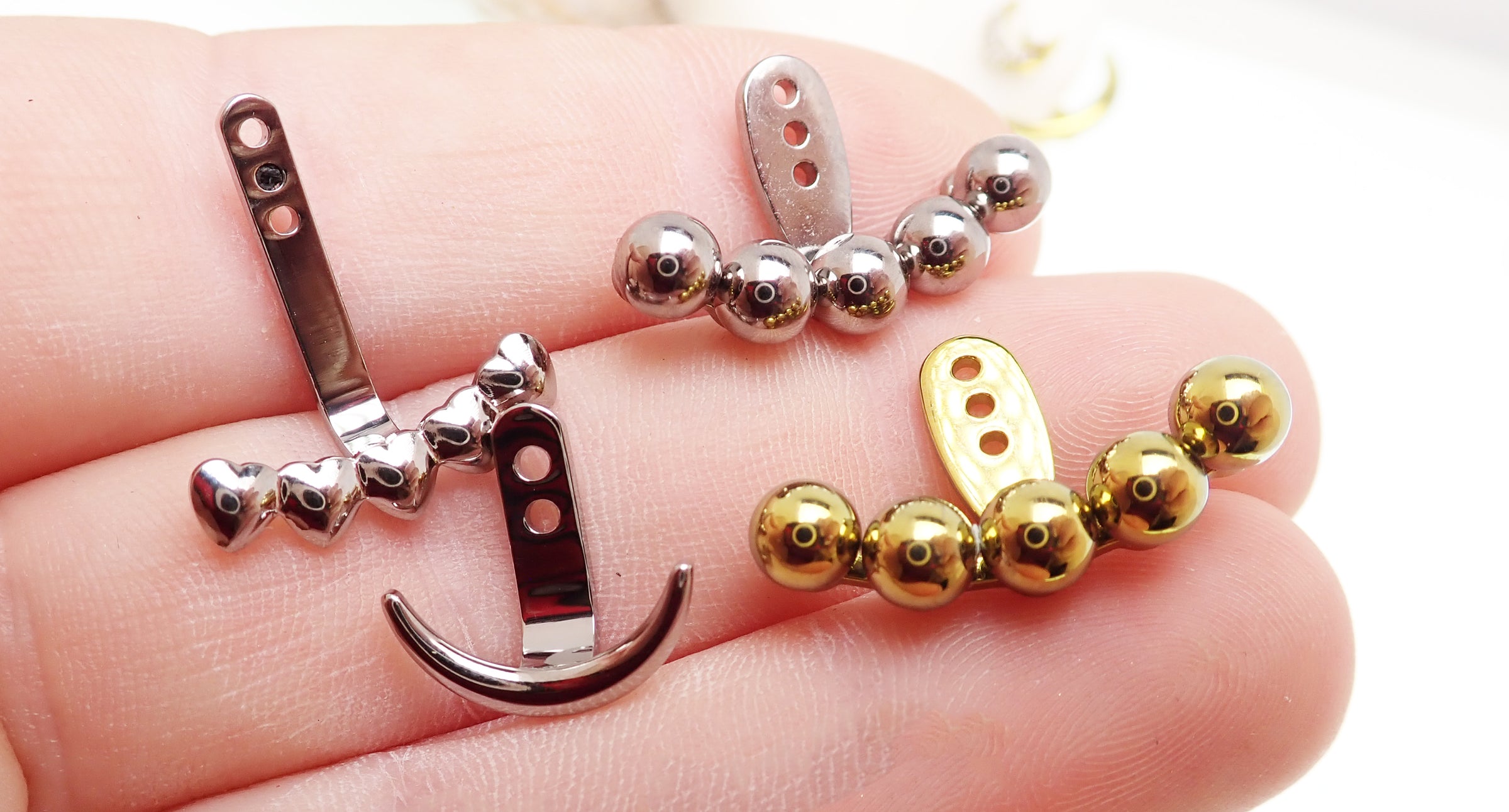 Pair of Body Clickers titanium implant earrings with jacket hangers, showcasing sleek, ball-shaped designs for a modern jewelry look.