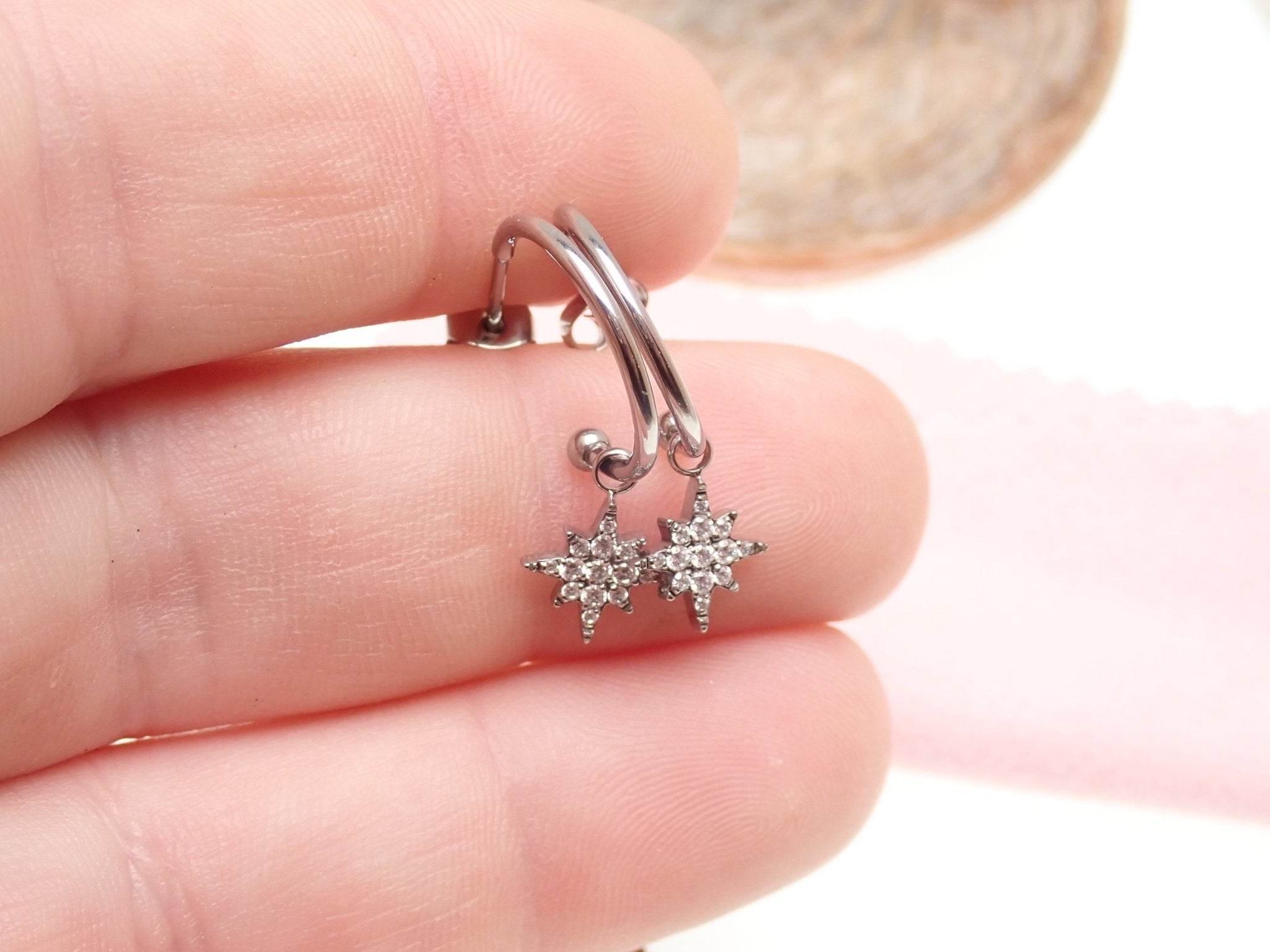 Titanium hoop earrings with charms from Body Clickers Body Jewelry, 20g, featuring sleek silver designs and decorative charms.