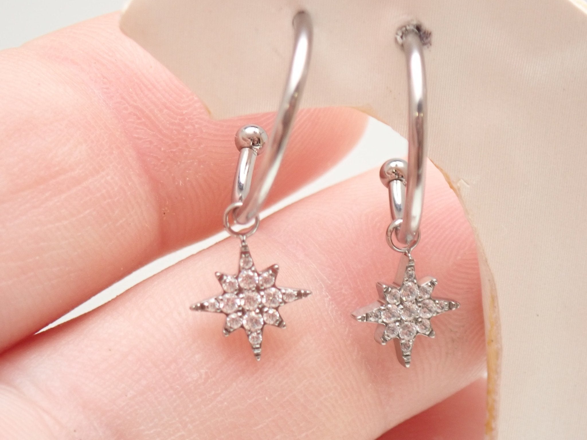 Titanium hoop earrings with charms, 20g Body Clickers body jewelry, featuring sleek silver titanium hoops with decorative charms.