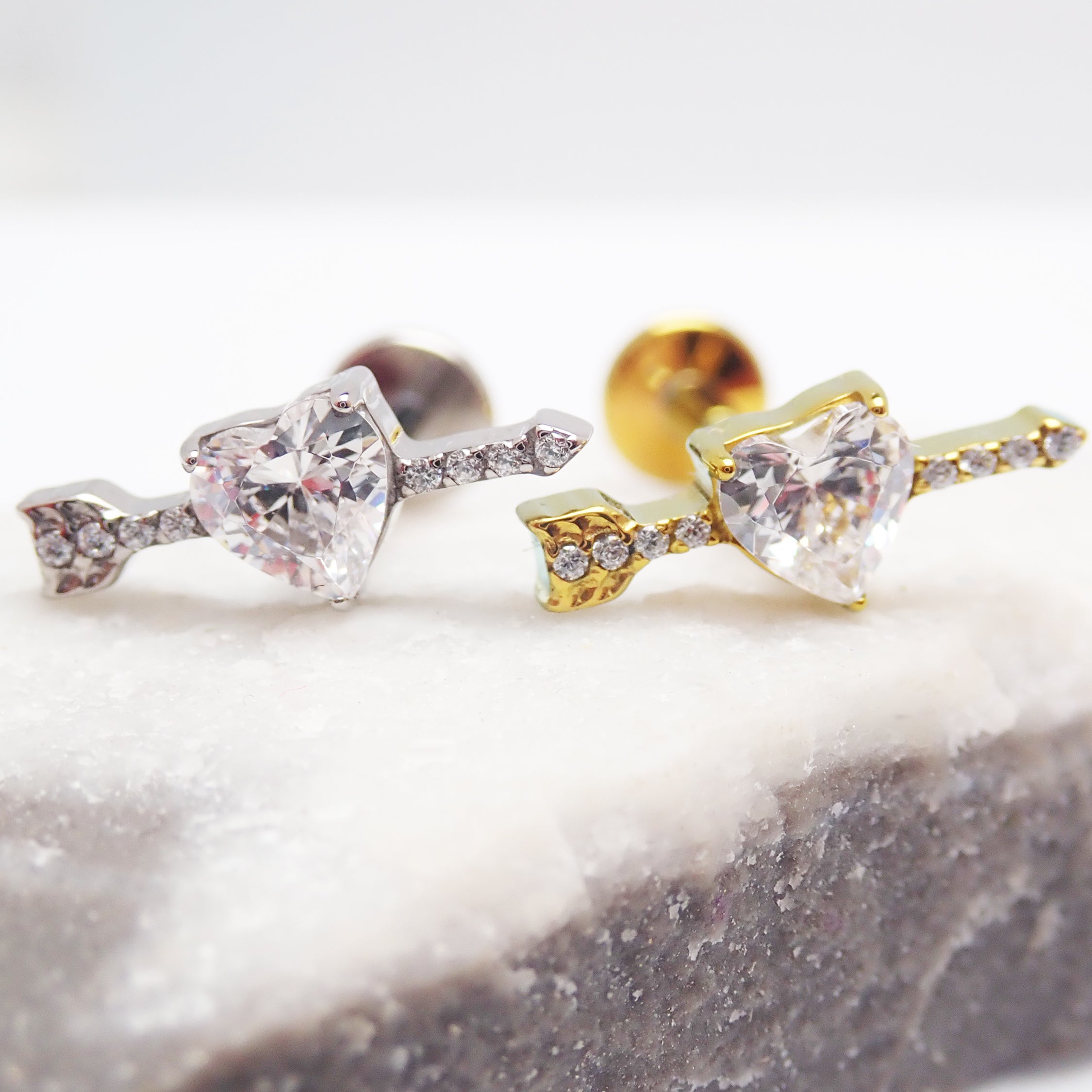 Body Clickers 18g titanium CZ arrow through heart flatback labret piercing earrings, featuring a sleek arrow design and heart motif.