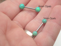 Titanium barbell nipple piercing with kiwi green fire opals from Body Clickers, 14g, 1.6mm, 8mm bar length, 5mm opals.