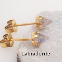 Pair of gold labradorite earrings displayed leaned against a stone with the stone type labeled at the bottom