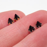 silver and gold onyx cone earrings displayed in between fingers 
