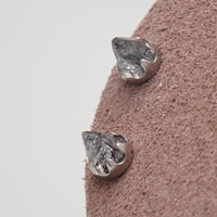 A  pair of silver tourmalated quartz cone earrings on a brown display