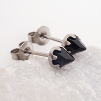 silver onyx cone earrings leaned against a stone with a white background 