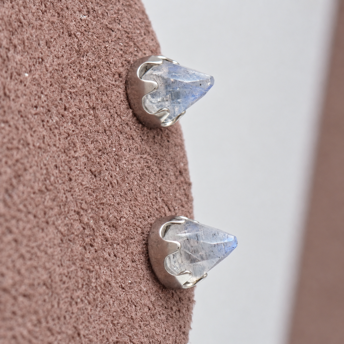 Pair of silver labradorite cone earrings on a brown  display
