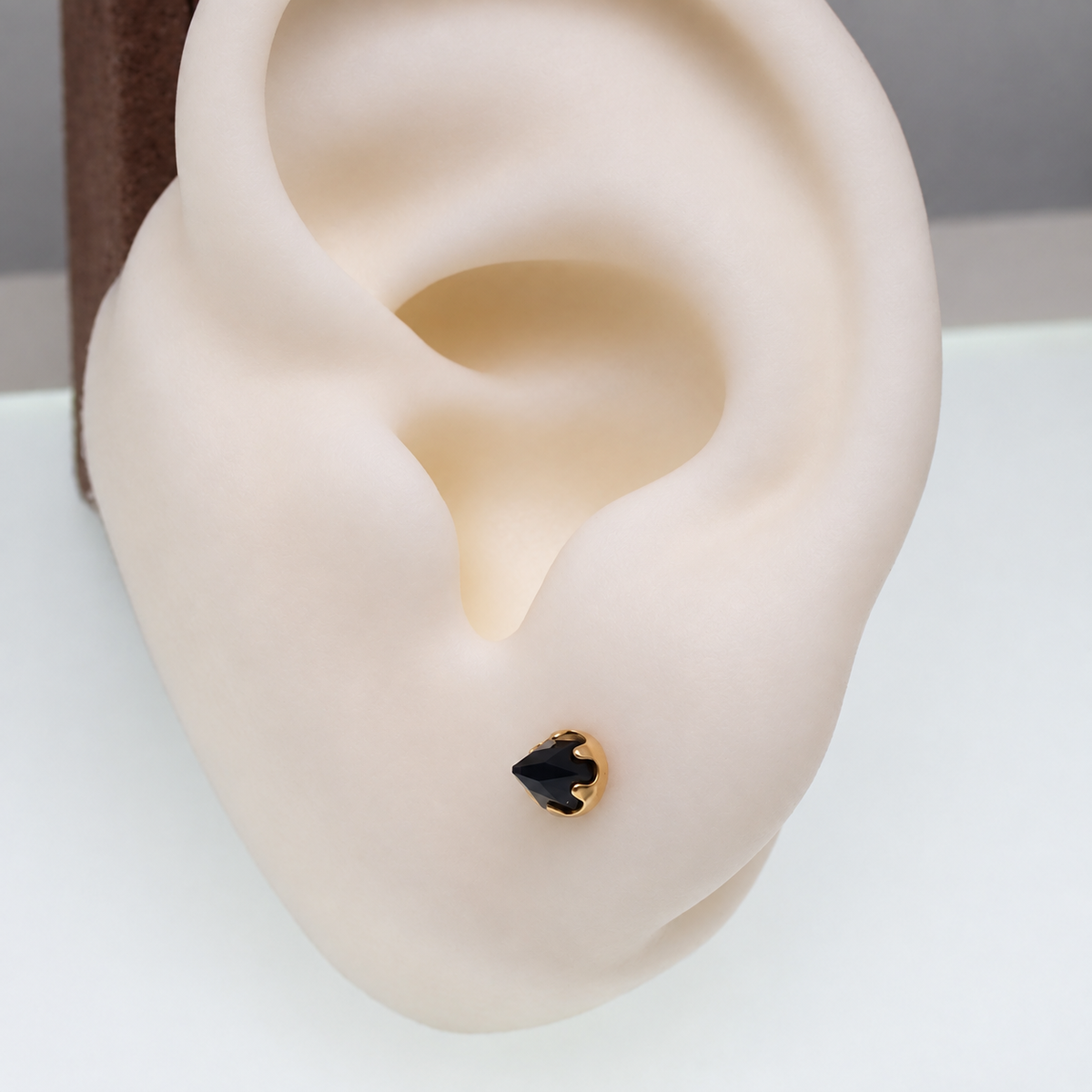 a gold onyx cone earring in a silicone ear model