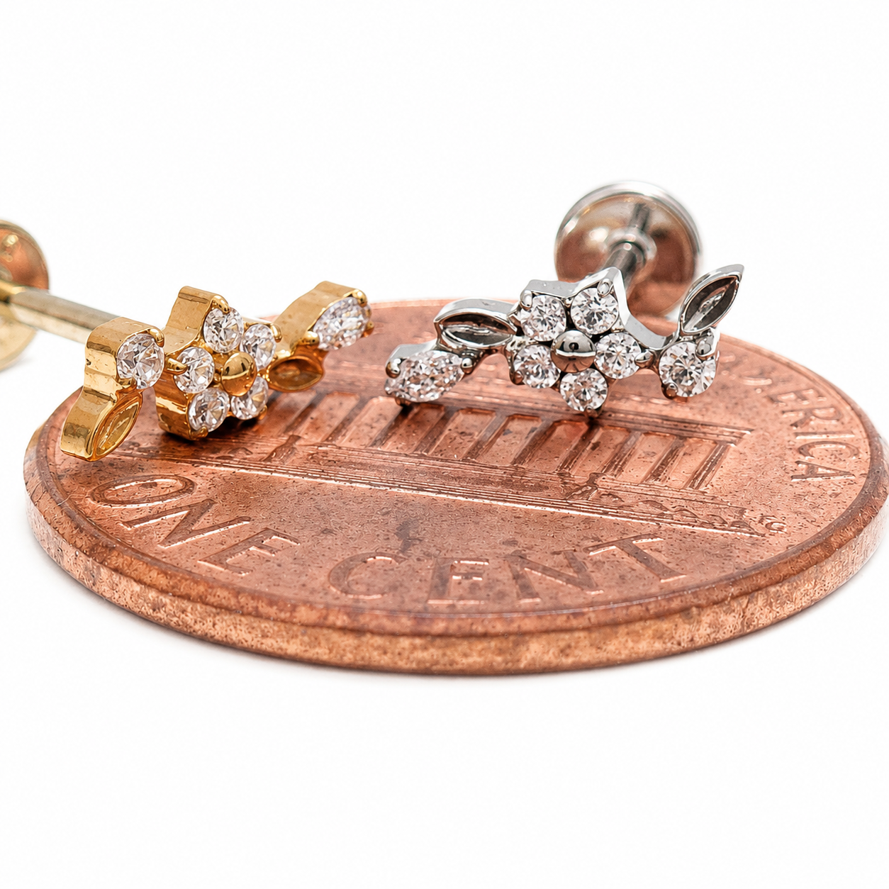 Dainty flower titanium flatback labret piercing earrings with 0.9mm threaded design, displayed next to a penny for size reference.