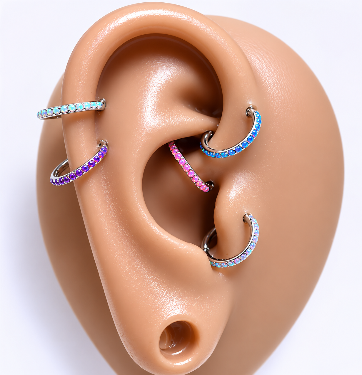 Close-up of an ear with multiple colorful hoop earrings on a white background