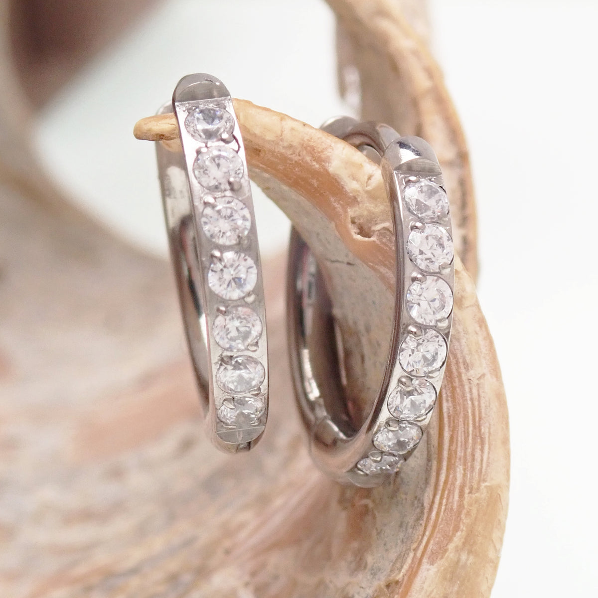 titanium Chunky Hoop earrings with clear cz on a wooden display
