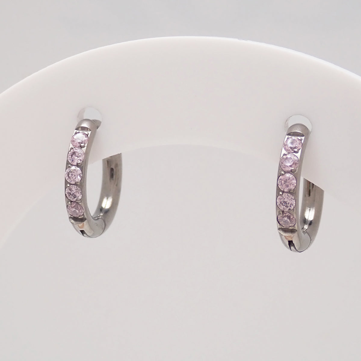 Titaniumm hoop earrings with pink CZ on a white display