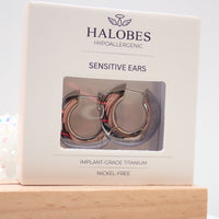 Pair of Body Clickers titanium silhouette huggie earrings with hinged clickers, 10mm size, in packaging.