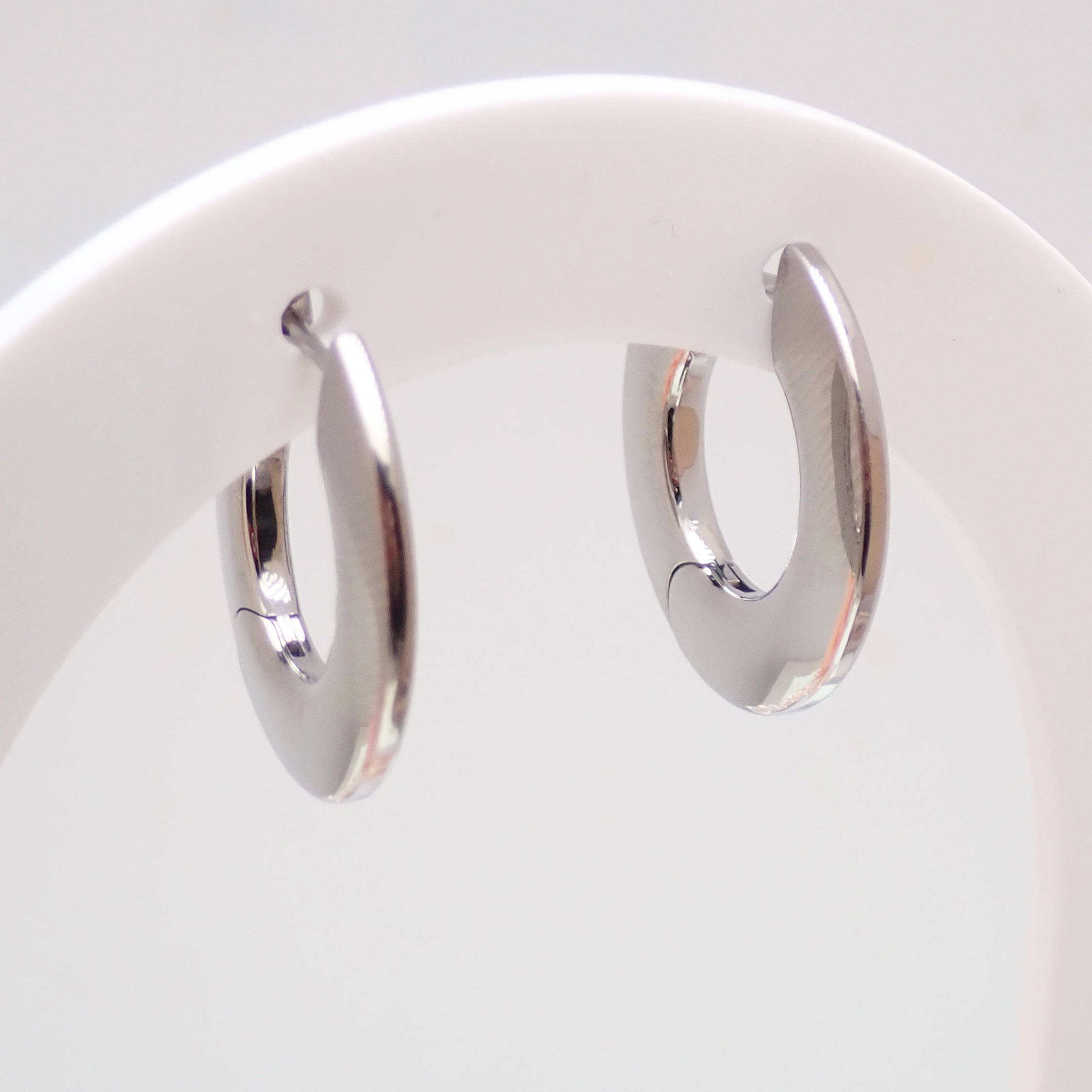 Silver titanium implant silhouette huggie earrings with hinged clicker closure, 10mm diameter, sold in pairs by Body Clickers.