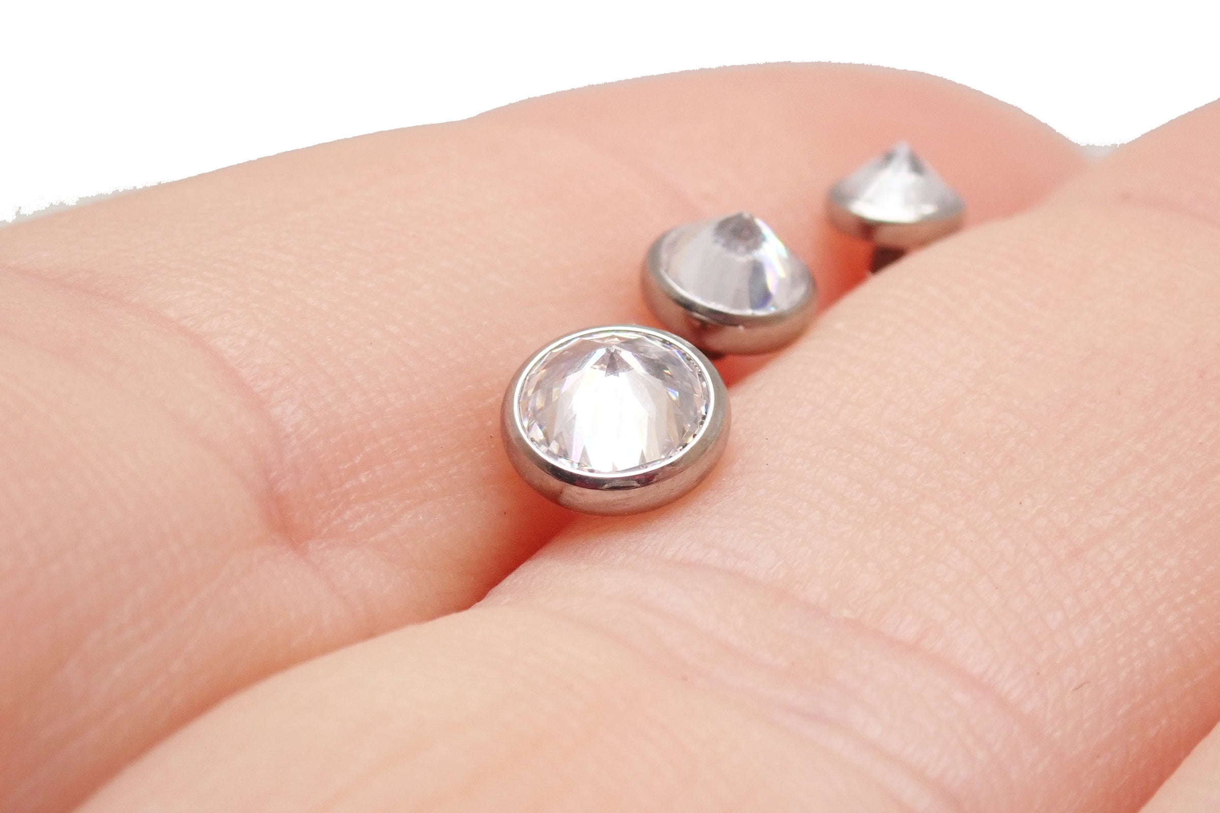 Magpie 14g internally threaded dermal attachment with CZ top, showing the small size and detailed threading in hand.