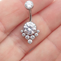 Magpie CZ titanium belly ring, 10mm to 12mm, featuring sparkling stones and a sleek curved design on a hand.