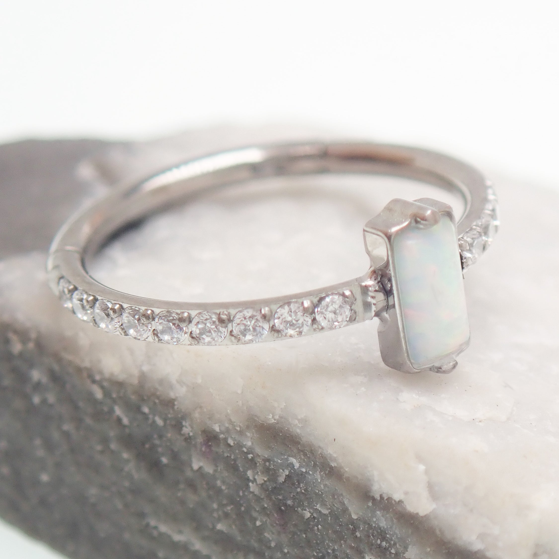 Rectangular white opal CZ titanium clicker earring in 16g size, 11mm, by Magpie Body Jewelry, shown in close-up.
