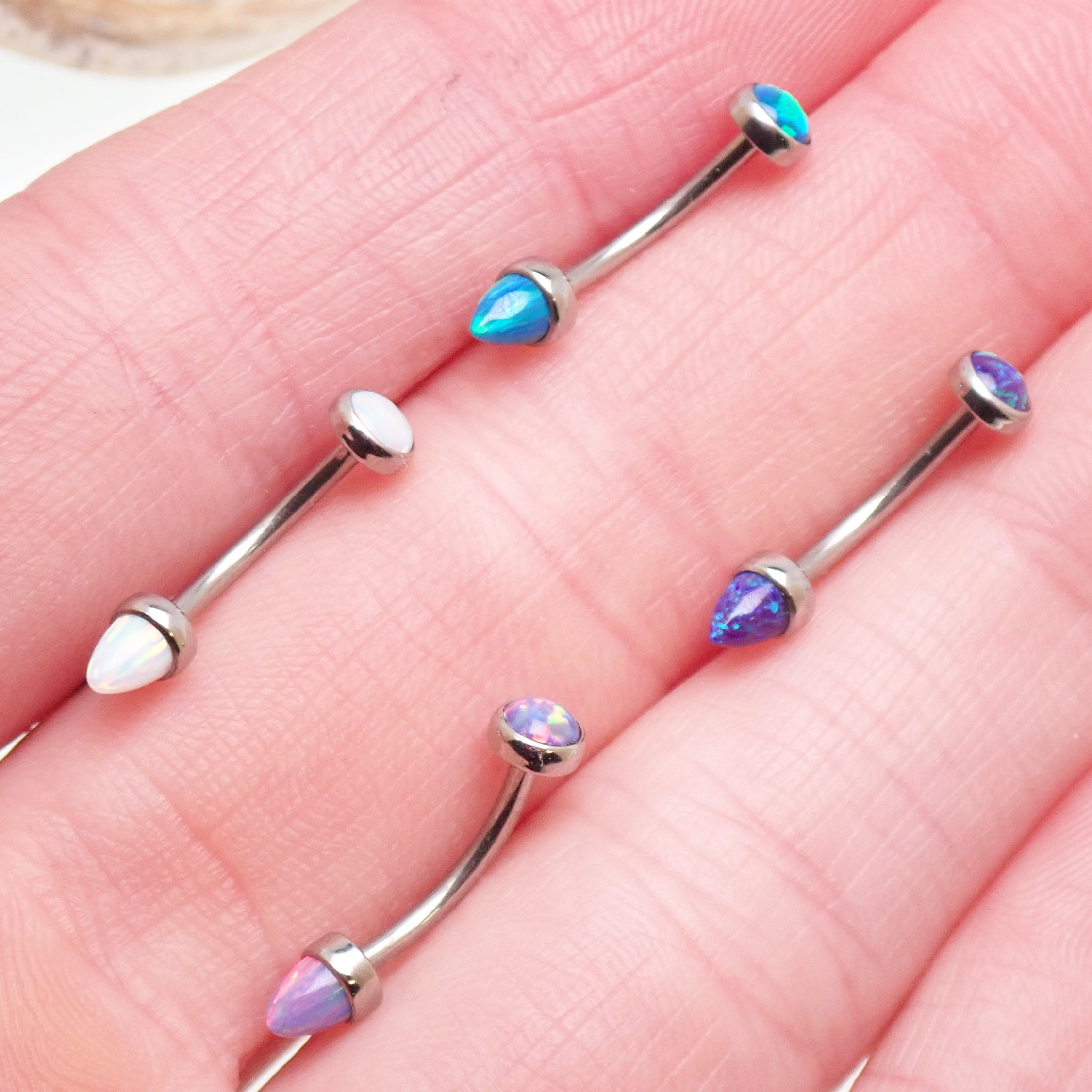 Body Clickers opal and titanium push-fit curve body jewelry with flat and cone ends, available in 14g, 16g, and 18g sizes.