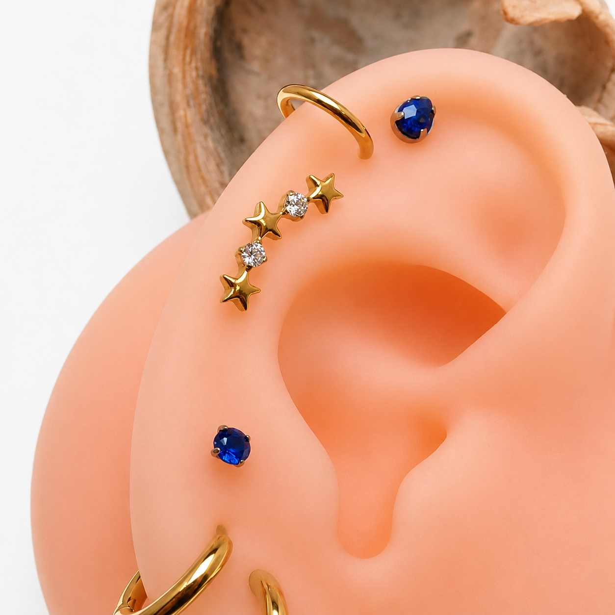Gold titanium helix curve earrings with star CZ accents, suitable for labret piercing in 14g, 16g, and 18g sizes.