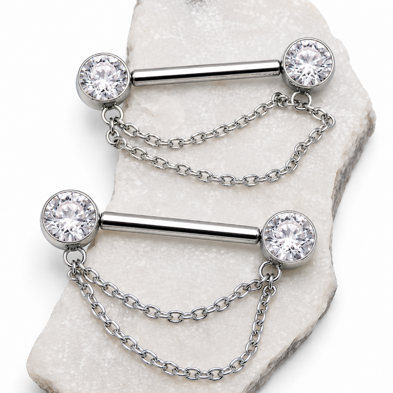 Silver barbell with chain and clear gemstones on a marble surface