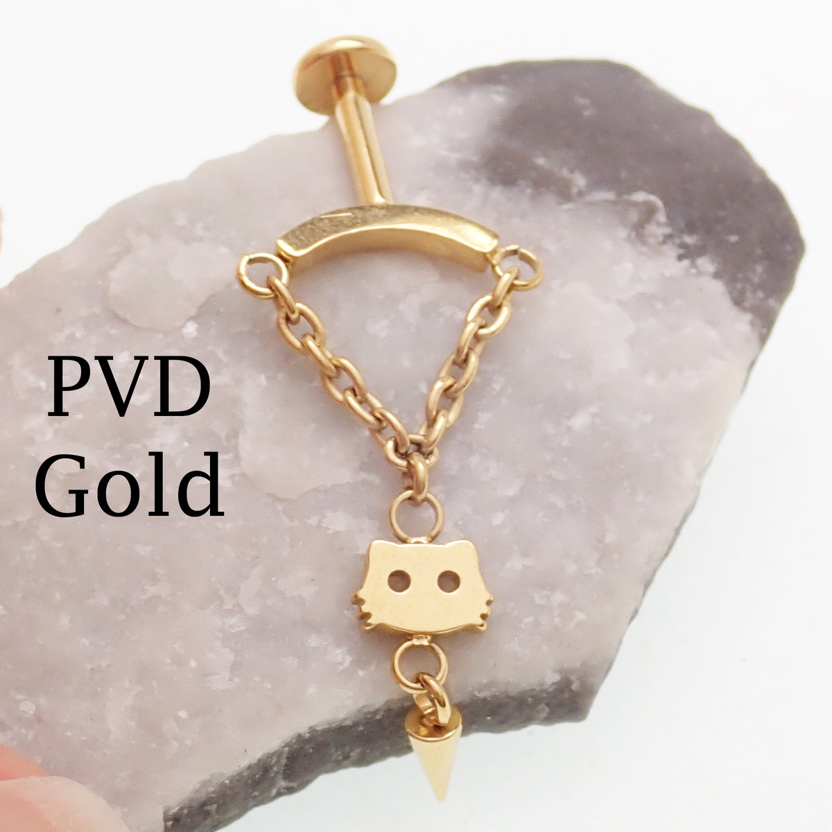 Gold dangly vertical helix piercing sitting on a rock with "PVD Gold" labeled next to the jewelry 
