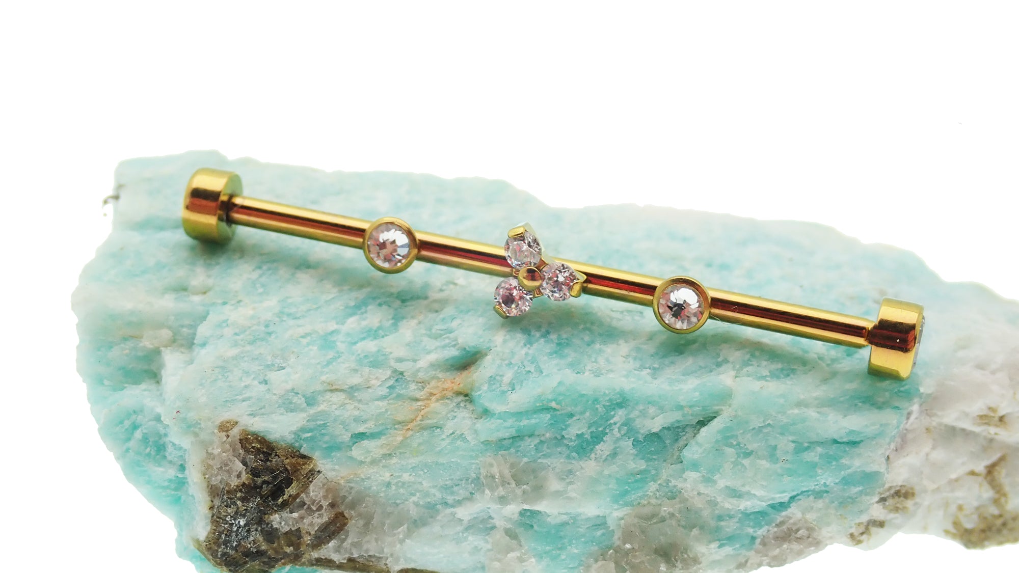 Gold industrial scaffold piercing with clear CZ stones, tri-flower design, and titanium bar, by Body Clickers.
