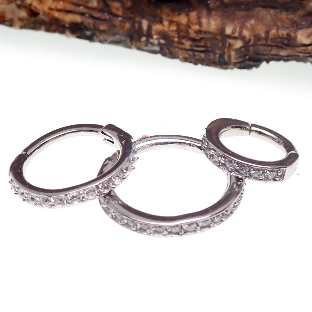 Close-up of a CZ inlaid thick steel hoop body jewelry with hinge clicker from Body Clickers.