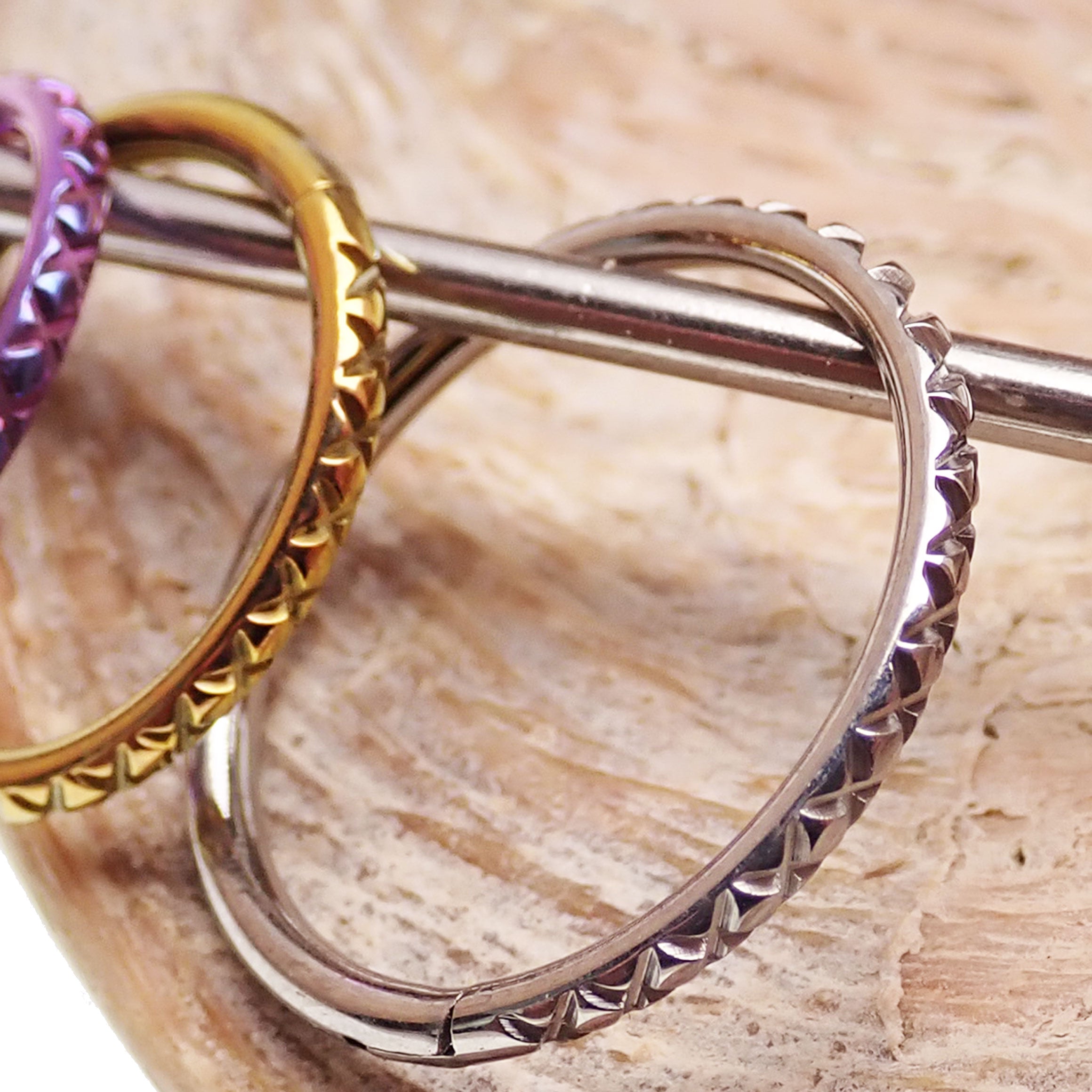 Titanium crisscross-etched clicker body jewelry in 16g with engraved design, featuring 8-12mm size options.