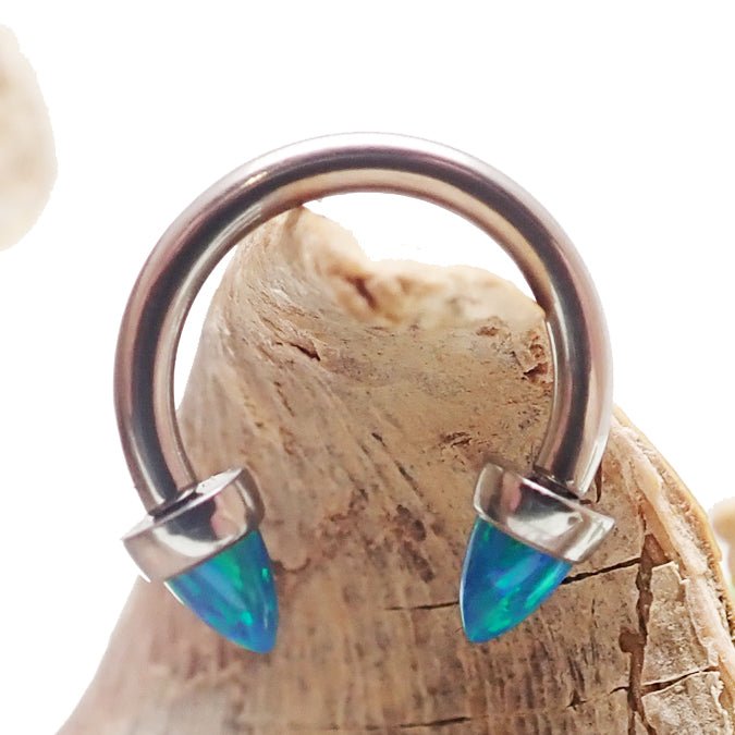Peacock blue 4mm cone horseshoe piercing in 14g body jewelry by Body Clickers, shown in close-up detail.