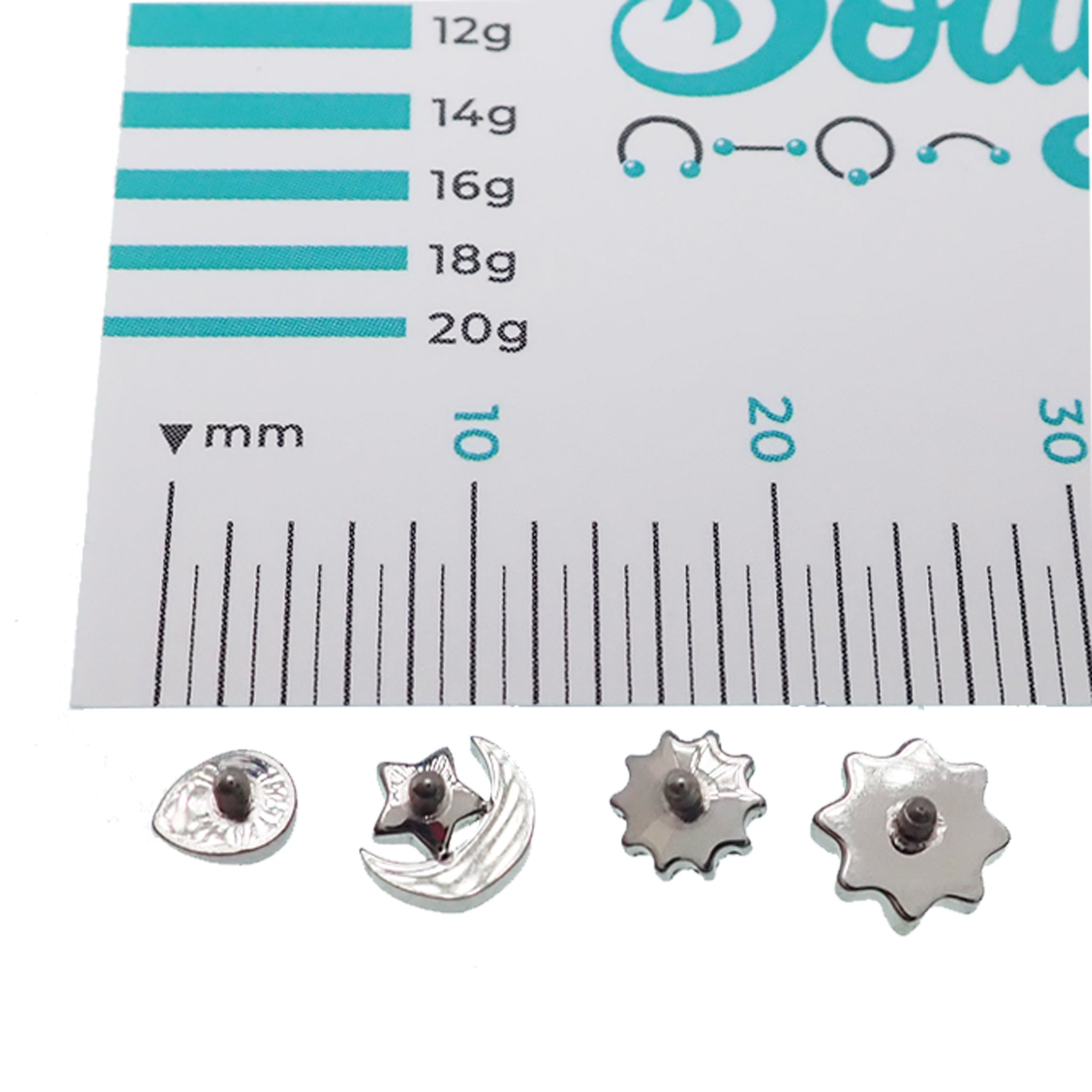 CZ Daisy, Opal Tear, and CZ Moon dermal titanium tops for 14g body jewelry, shown on a jewelry display.
