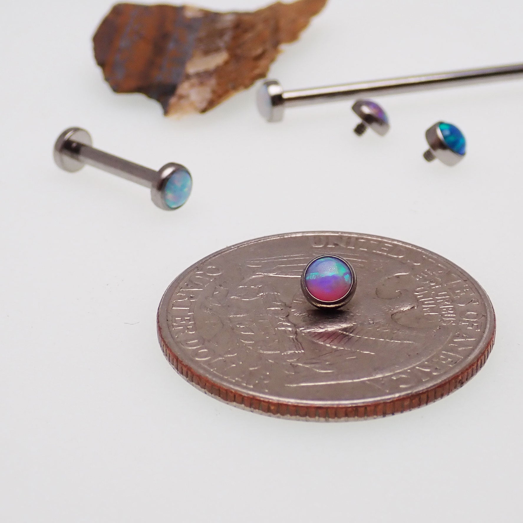 Titanium straight barbell body jewelry with flat opal ends, 16g, from Body Clickers, featuring sleek blue-colored accents.