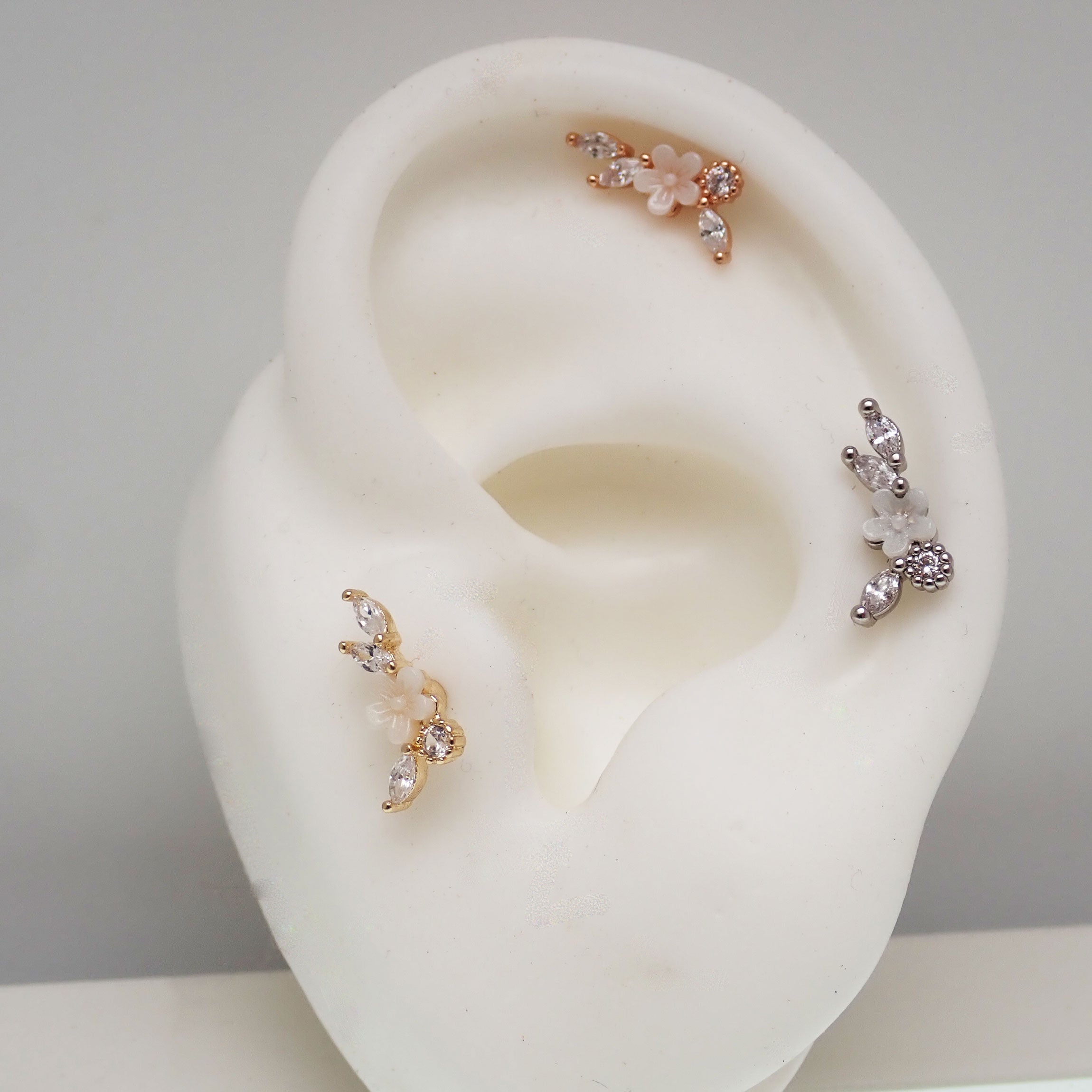 Brass helix flower piercing with CZ stones in 16g body jewelry, featuring a detailed steel and brass floral design.