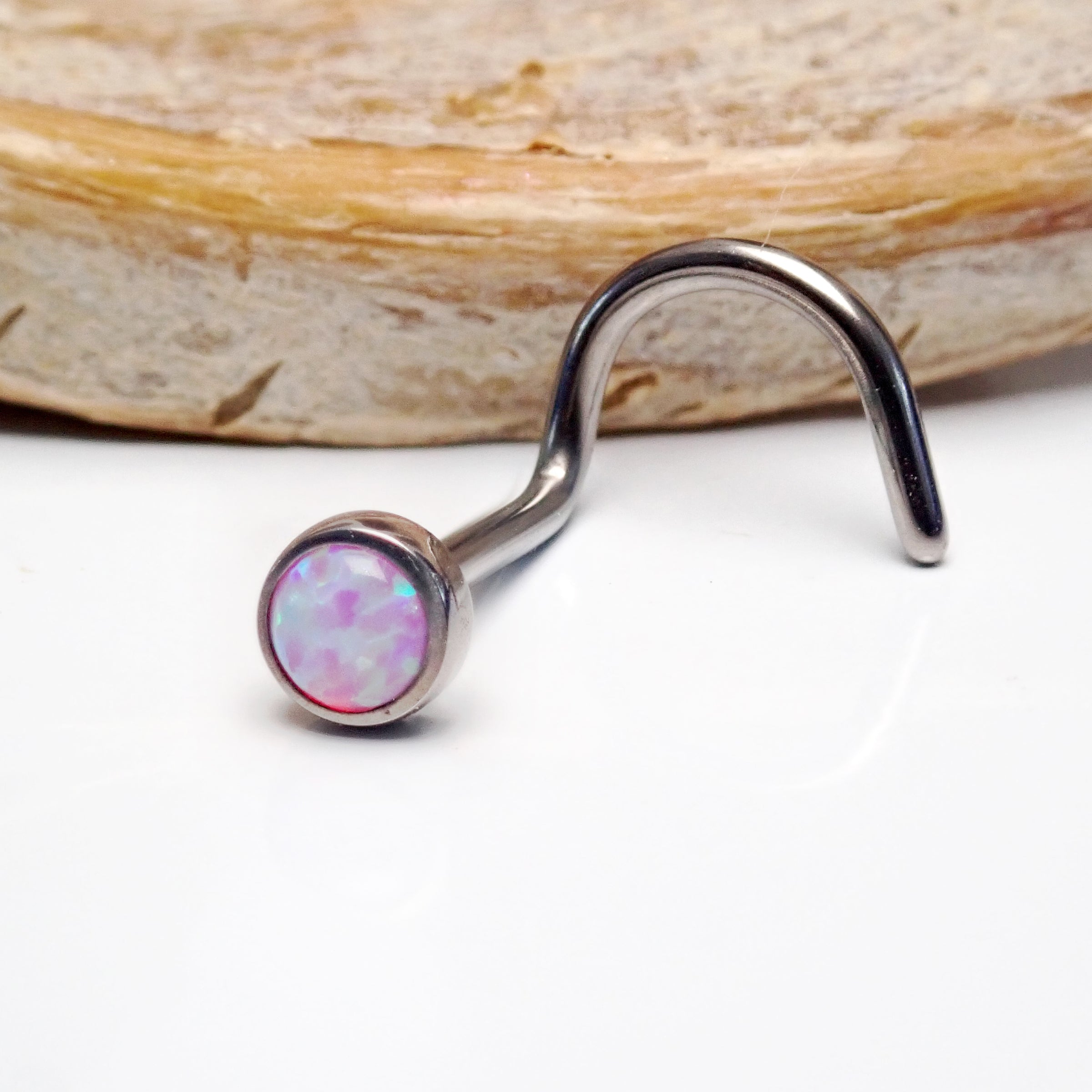 Opal nose curl body jewelry by Body Clickers, 20g gauge, featuring a bubblegum-colored opal stone and curved design.