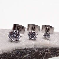 Three pairs of clear CZ prong earrings from Body Clickers body jewelry collection, showcasing sparkling crystal accents.