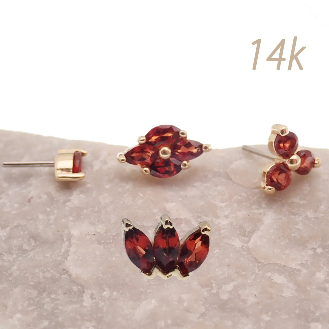 Four-piece set of 14K gold garnet threadless labret piercings with natural stone garnets and flat back design by Body Clickers Body Jewelry.