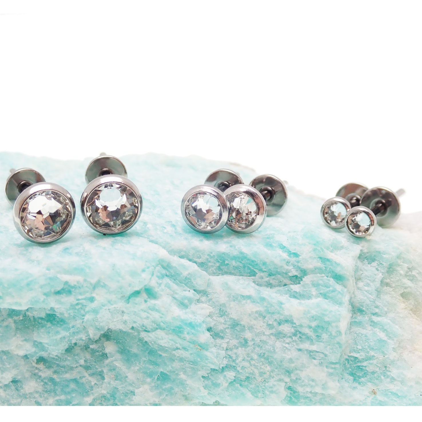 Pair of titanium zircon stone earrings with 3mm clear crystals, featuring sleek, modern design from Body Clickers Body Jewelry.