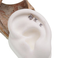 Clear triple CZ flat back body jewelry in 14g, 16g, and 18g sizes by Body Clickers, shown in a close-up image.
