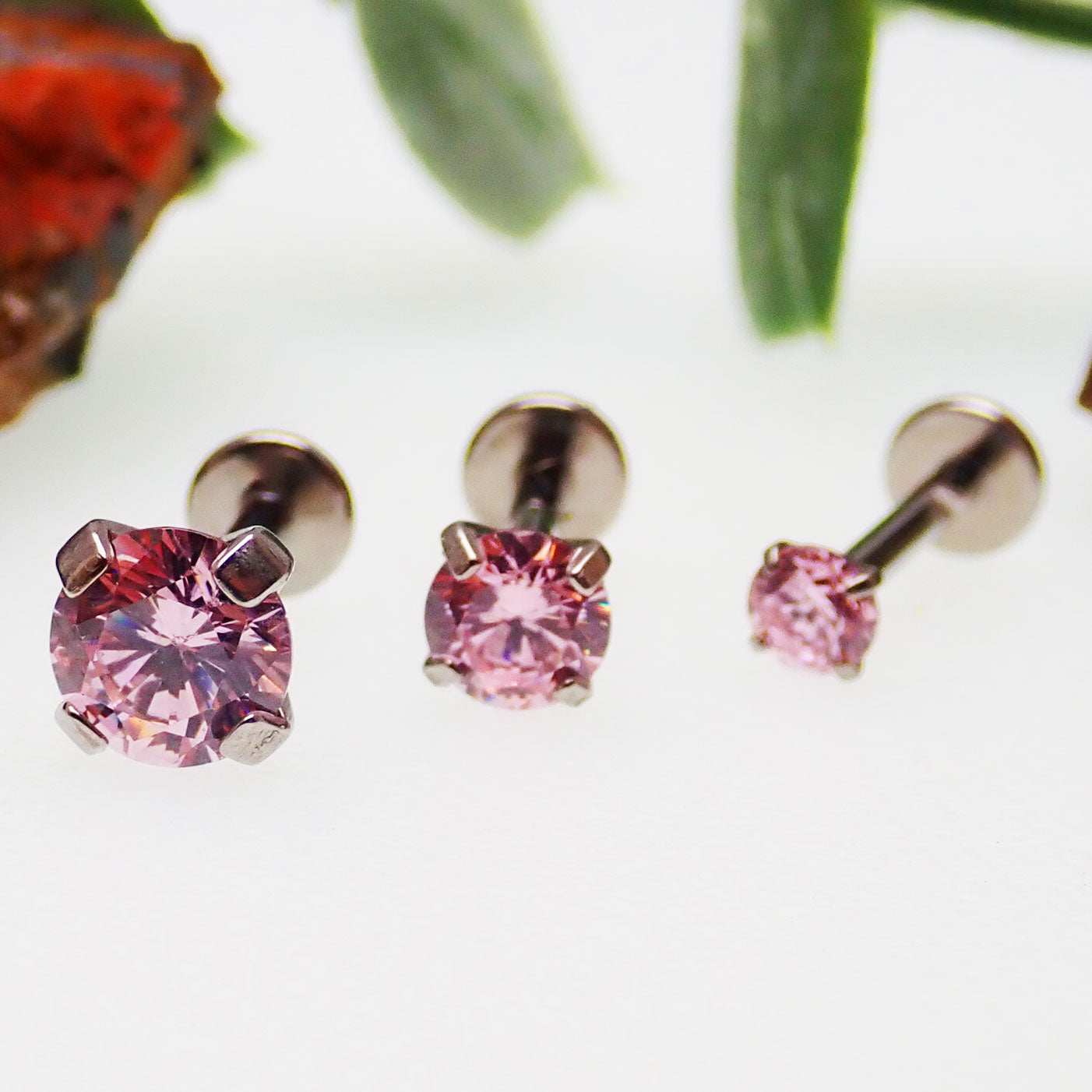 Set of three pink Body Clickers body jewelry with triple CZ stones in 14g, 16g, and 18g flat back designs.