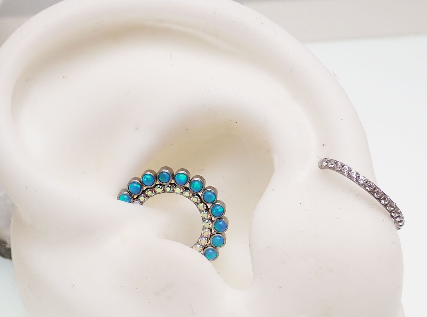 Double row peacock blue opal and clear CZ stones clicker earring from Body Clickers, 16g, with sparkling gemstone accents.