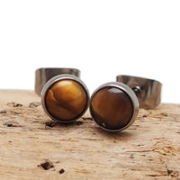 Pair of Tiger's Eye titanium earrings from Body Clickers, featuring smooth oval stones and sleek metal hooks.
